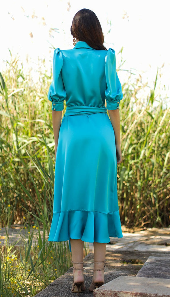 Midi dress with tuxedo collars, crossover, with lacing, ruffle at the bottom and puffed sleeves with cuffs and buttons. It has a separate sash belt. Made with turquoise satin fabric.