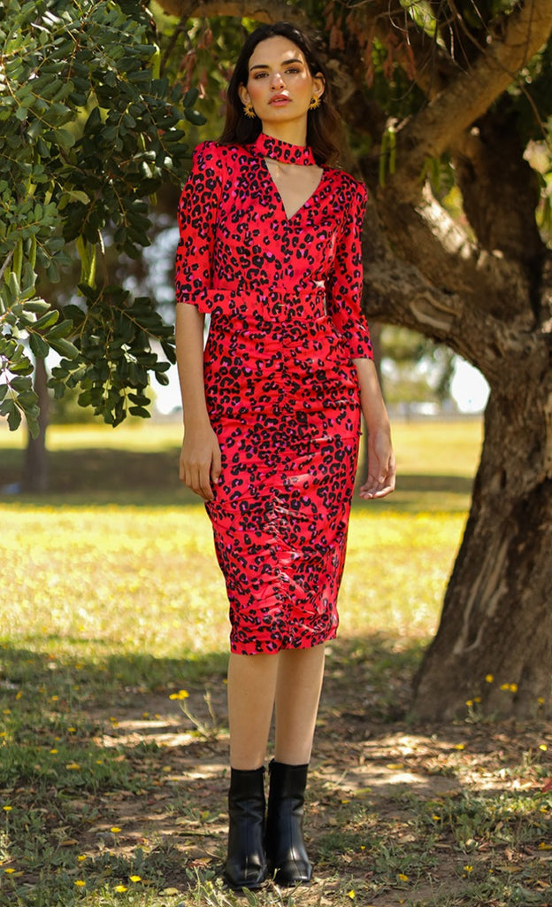 Fitted midi dress with V-shaped neckline and neck strap fastened at the back with loops and buttons. Gathers at the front of the skirt, 3/4 sleeves, includes belt. Made with red animal print elastic satin fabric.