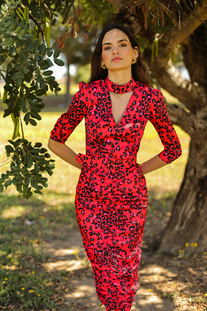 Fitted midi dress with V-shaped neckline and neck strap fastened at the back with loops and buttons. Gathers at the front of the skirt, 3/4 sleeves, includes belt. Made with red animal print elastic satin fabric.